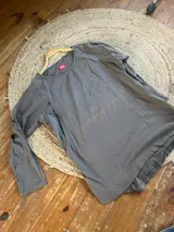 Remerón oversize de jersey de algodón color gris, diseñado para embarazo y lactancia. Presenta cuello redondo, mangas largas, espalda más larga, tajos laterales y bajos redondeados, con aperturas ocultas para amamantar.