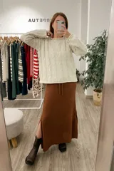 Sweater tejido color arena con diseño de espiga, cuello redondo y mangas largas.