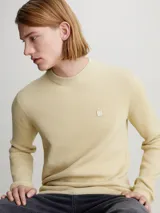Sweater color crema de algodón con textura de canalé, cuello redondo e insignia de Calvin Klein Jeans bordada en el pecho.