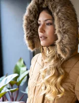 Campera de abrigo negra marca Michael Kors, con capucha desmontable con borde de piel sintética, cierre central con botones a presión y cierre oculto, bolsillos delanteros con cierre, puños elastizados, cintura con pasadores y cinto elastizado con hebilla.