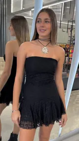 Vestido corto strapless de encaje negro, con diseño ajustado al cuerpo y falda con volado en el ruedo.