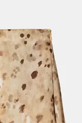 Falda mini de tiro medio con diseño asimétrico y bajo acabado en volantes. Presenta un estampado de manchas en tonos tierra y cierre lateral con cremallera oculta.
