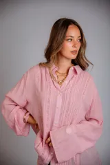 Camisa rosada con detalles de broderie en la parte delantera y mangas anchas.