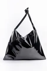 Maxibolso Judy de Mishka, confeccionado en símil charol negro con efecto arrugado. Cuenta con apertura de broche imán, asas para llevar al hombro con detalle de nudo y un diseño grande y liviano.