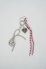 Llavero decorativo con mosquetón en forma de corazón, cadena de esferas plateadas con dije de corazón, portafotos en forma de corazón y cordones de tela estampada en color bordó.