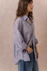 Camisa lila oversize de algodón con bordado floral calado tipo broderie, cuello camisero, manga larga y abotonadura frontal.