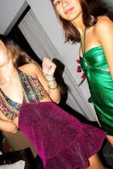 Vestido corto negro con estampado de plumas doradas, escote en V, breteles finos cruzados en la espalda, cut-outs laterales y volado en el ruedo.