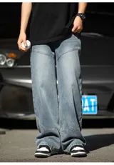 Pantalón de jean de corte relajado y ancho, color azul medio desgastado, con costuras decorativas en diagonal en la parte delantera de las piernas y bolsillos traseros.