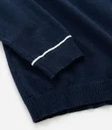 Suéter de punto en color bordó con corte slim, cuello polo y mangas largas. Presenta detalles de líneas blancas en contraste en el cuello y los puños, con acabado acanalado.