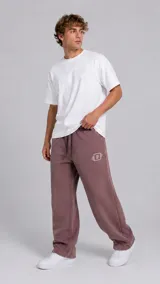 Pantalón tipo jogger de corte holgado en color bordó, con cintura elástica y cordón de ajuste. Presenta un pequeño logo bordado en color blanco en la pierna izquierda.