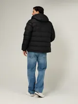 Campera puffer Tommy Hilfiger de color negro, acolchada con diseño horizontal, capucha integrada y cierre frontal de cremallera. Cuenta con bolsillos laterales con cierre y el logo bordado en el pecho.