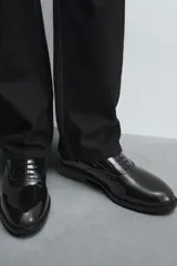 Zapato de vestir tipo derby color negro acharolado, con horma en punta y suela con ligero tacón.