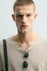 Jersey de punto de corte relajado, con cuello redondo amplio y mangas largas. Presenta un diseño de rayas horizontales finas en contraste sobre fondo beige.