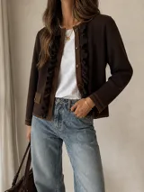 Chaqueta de punto color marrón chocolate, con diseño de volados en los bordes frontales, cierre de botones y bolsillos laterales con solapa.
