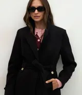Saco femenino de corte midi confeccionado en polyvelour, con diseño cruzado, cuello tipo blazer, mangas largas con detalles en puños, cierre frontal con lazo ajustable en la cintura y botones metalizados decorativos.