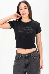 Remera crop negra ajustada al cuerpo, con mangas cortas y cuello redondo, con estampa tipográfica frontal.