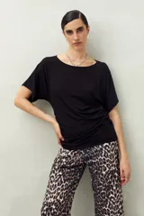 Remera negra de manga corta, confeccionada en modal, con cuello bote y frunces laterales.