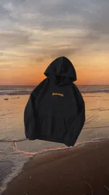 Hoodie oversize negro con capucha y estampado en la espalda con diseño inspirado en surf y olas en tono naranja.