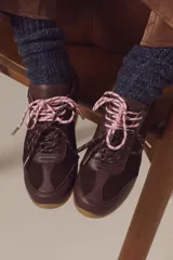 Zapatilla de cuero marrón con paneles de gamuza y cuero liso, suela de goma color caramelo y cordones bicolores en rosa y blanco.