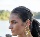 Aros colgantes grandes de metal dorado con diseño irregular y textura ondulada.