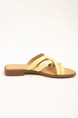 Sandalias planas de cuero color amarillo, con múltiples tiras finas entrelazadas en el empeine, suela baja y plantilla marrón.