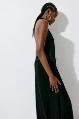 Top halter en tejido de lyocell con brillo, escote drapeado, botones en la nuca, cierre oculto en un lateral y bajo asimétrico.