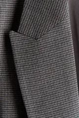 Blazer de sarga con diseño a cuadros, solapas de pico y frente abierto. Cuenta con bolsillos delanteros ribeteados con solapa y mangas diseñadas para ser remangadas, revelando un forro a rayas. Prenda completamente forrada.