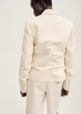 Blazer de corte recto y diseño estructurado, confeccionado en una mezcla de algodón y lino. Presenta cuello con solapas de muesca, cierre frontal con botones, mangas largas con puños abotonados y dos bolsillos laterales con solapa. Incluye forro interior y abertura posterior en el bajo.