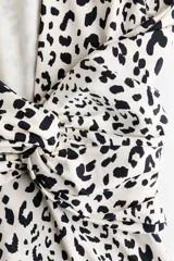 Vestido midi de punto entallado con estampado de leopardo, mangas largas y espalda abierta con detalle cruzado en la cintura.