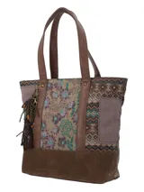 Cartera tipo tote con diseño patchwork que combina paneles de tela estampada con motivos geométricos y florales, y detalles en cuero sintético marrón. Incluye asas largas, base reforzada y un colgante decorativo de borlas y cadenas metálicas en el lateral.