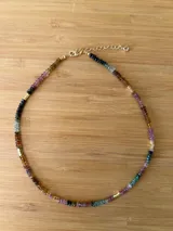 Gargantilla corta con cuentas facetadas de turmalina multicolor y detalles de cuentas doradas. Cierre de mosquetón dorado con cadena de extensión.