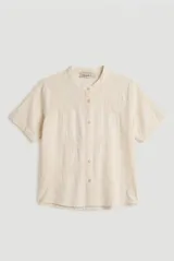 Camisa de manga corta color blanco con cuello mao y cierre frontal de botones. Presenta detalles bordados tono sobre tono en el canesú y diseño de corte recto.