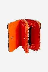 Billetera pequeña con cierre perimetral en color fucsia y cuerpo estampado con diseño animal print en tonos grises y negros. Incluye logo de la marca grabado en el frente y bolsa de tela protectora.