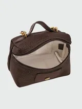 Cartera crossbody pequeña de cuero granulado en color marrón oscuro, con diseño estructurado, cierre superior con cremallera y detalle de logo metálico en el frente.