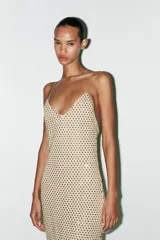 Vestido largo color dorado, confeccionado en tejido tipo red con aplicación de strass, escote pico y tirantes finos. Incluye forro interior y cierre en espalda con cremallera oculta en costura.