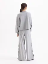 Pantalón de corte recto y silueta holgada, confeccionado en tejido rústico de algodón color verde militar. Presenta cintura con elástico interno y detalles de broches metálicos a presión en los laterales.