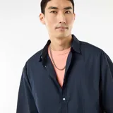 Camisa de manga corta azul marino confeccionada en popelín, con cuello camisero clásico y cierre frontal de botones.
