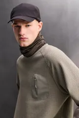 Camiseta relaxed fit de color verde militar, confeccionada en tejido con estructura waffle. Tiene cuello redondo, manga larga con puño elástico y un bolsillo plastrón con cierre de cremallera en el pecho.