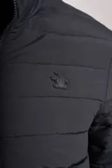 Campera acolchada negra con cierre frontal, cuello alto y diseño de costuras horizontales. Presenta un ajuste entallado y tejido exterior resistente al agua.