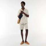Bermuda de corte clásico confeccionada en tejido ligero de color beige con diseño de rayas verticales oscuras. Cuenta con bolsillos laterales y pretina con elástico.