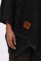 Ruana tejida de punto en mezcla de algodón y lurex, con acabado brillante. Presenta un diseño holgado con escote en V y etiqueta de cuero sintético con logo de la marca en el frente.