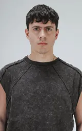 Remera sin mangas (tipo musculosa) de algodón, color negro con efecto gastado (acid wash). Presenta recortes diagonales en el frente y mangas cortas caídas, con cuello redondo.