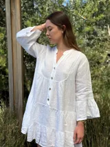 Vestido amplio de lino color verde lima, con cuello mao y abertura frontal con botones de coco. Presenta un diseño con canesú fruncido y volados en los puños de las mangas largas.