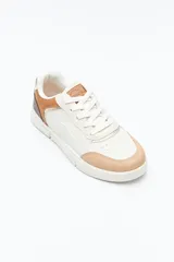 Zapatilla urbana blanca de mujer, con silueta moderna y líneas limpias. Presenta detalles en poliuretano liso y un panel plateado en el talón. La suela es de perfil recto y firme.