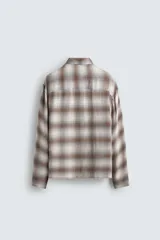 Camisa relaxed fit de manga larga con cuello solapa, confeccionada en tejido con mezcla de viscosa. Presenta un bolsillo plastrón en el pecho, bajo con aberturas laterales y cierre frontal de botonadura. El diseño es a cuadros en tonos beige y marrón.