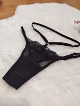 Tanga de diseño sofisticado confeccionada en una combinación de microtul transparente y encaje. Presenta un corte tipo colaless con tiras elásticas regulables en la cintura y laterales, permitiendo un ajuste personalizado. El panel frontal combina una sección de encaje con una base de microtul y un refuerzo de algodón para mayor confort.