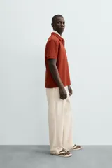 Polo de hombre color terracota con cuello solapa y cierre frontal de botonadura. Presenta un tejido texturizado tipo seersucker y un calce relajado.