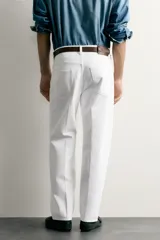 Jeans relaxed fit color blanco, de corte recto y tiro medio con tejido de algodón rígido. Cuenta con cinco bolsillos, efecto ligeramente lavado, perneras con raya de planchado y cierre frontal con cremallera y botón.