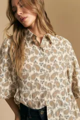 Camisa de manga corta con cuello camisero, confeccionada en tela estampada con diseño paisley en tonos negro, beige y azul.