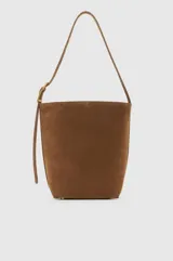Cartera tipo shoulder bag confeccionada en gamuza color marrón, con diseño minimalista, silueta amplia, correa ajustable con hebilla metálica dorada y herrajes a tono.